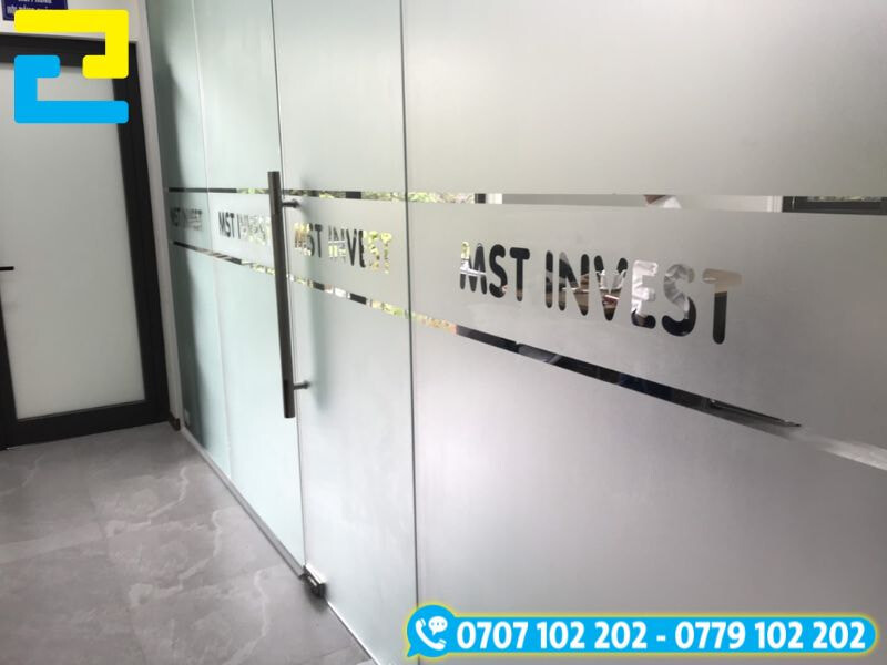In decal dán kính mờ cắt chữ hiện đại với logo công ty được cắt âm bản trên nền mờ, tạo điểm nhấn ấn tượng, vừa riêng tư vừa thu hút ánh nhìn cho cửa kính văn phòng