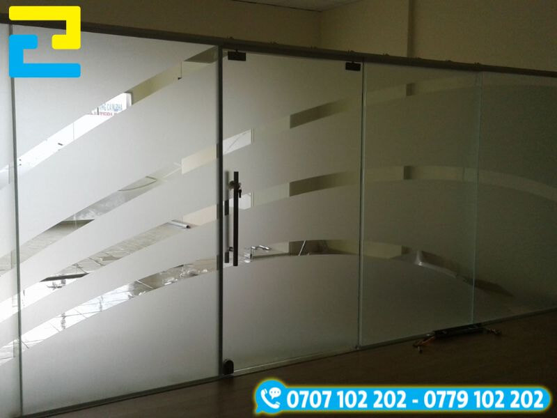 In decal dán kính mờ cắt họa tiết cách điệu với các đường cong cắt phá cách, tạo điểm nhấn thẩm mỹ cho vách kính văn phòng