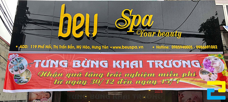 Mẫu 6: Bản in băng rôn khai trương spa được thiết kế với kiểu chữ đơn giản - nghệ thuật, kết hợp với hình ảnh dịch vụ, nền đỏ nổi bật