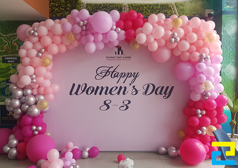 Mẫu 15: Backdrop ngày 8/3 có kiểu chữ nghệ thuật đẹp mắt, được thiết kế với tông màu trắng chủ đạo, kết hợp thêm bóng bay trang trí