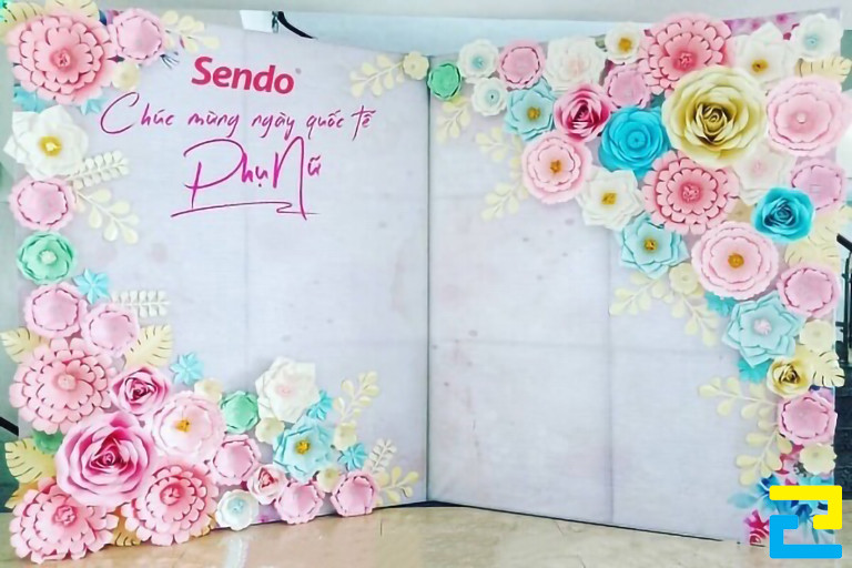 Mẫu 19: Backdrop Quốc Tế Phụ Nữ được thiết kế theo hình dạng cuốn sách, có tông màu trắng đẹp sang trọng, viền hoa đẹp mắt